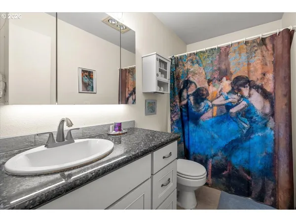 a bathroom with a granite countertop sink a toilet and a mirror