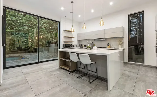 a kitchen with kitchen island a sink a stove a refrigerator and black cabinets next to a window