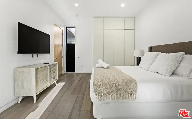 a spacious bedroom with a bed and a flat screen tv