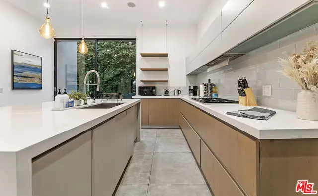 a kitchen with a sink a counter top space stainless steel appliances a large window and cabinets