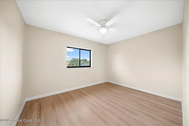 an empty room with wooden floor and fan