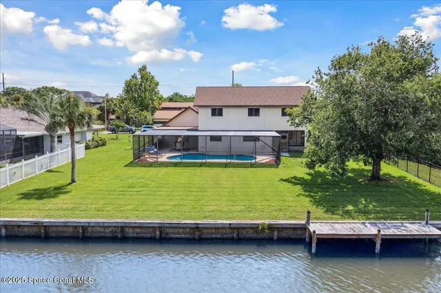 a view of a swimming pool with lawn chairs and a large tree