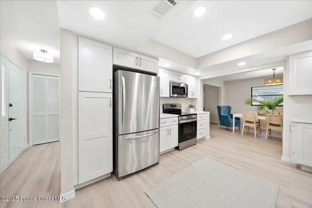 a kitchen with stainless steel appliances a dining table chairs and white cabinets