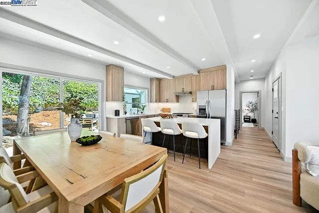 a kitchen with stainless steel appliances granite countertop a stove a refrigerator a sink dishwasher a dining table and chairs with wooden floor