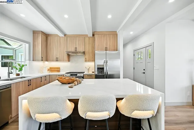 a kitchen with stainless steel appliances a dining table chairs and white cabinets