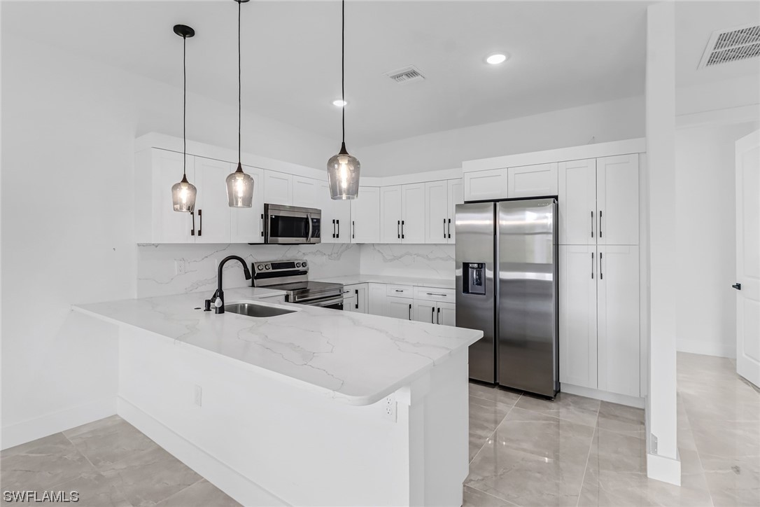 2607 4th Street Southwest Lehigh Acres, FL 33976 - Photo 5 of 21 a kitchen with stainless steel appliances granite countertop a sink a refrigerator and a window