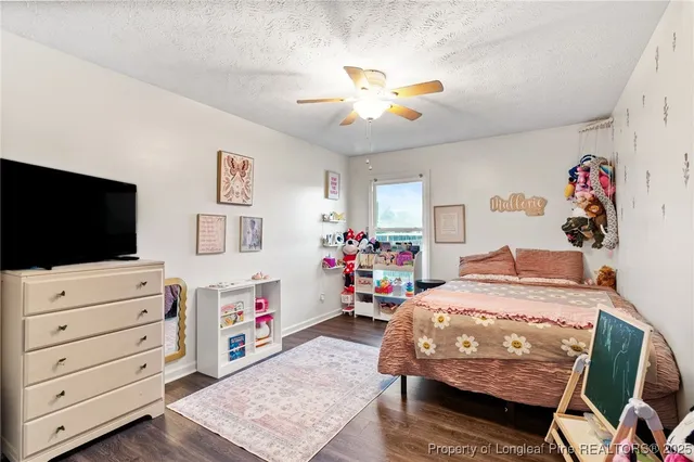 a bedroom with a bed a dresser and flat screen tv