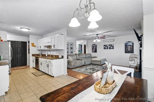 a kitchen with stainless steel appliances kitchen island granite countertop a refrigerator a stove and white cabinets with wooden floor