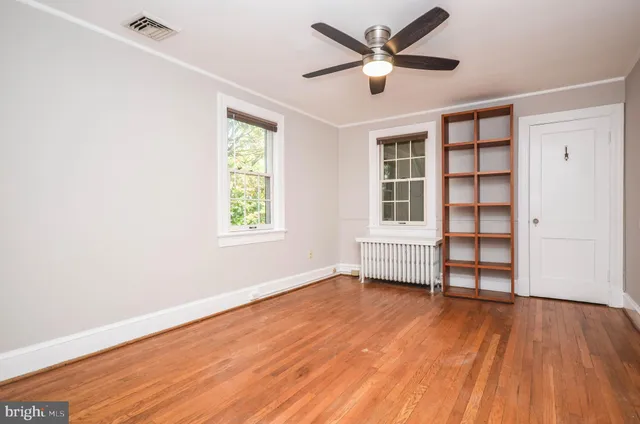 an empty room with wooden floor fan and windows