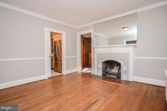 a view of an empty room with wooden floor fireplace and a window