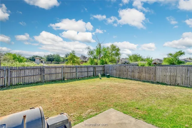 a view of a backyard with a large tree and wooden fence