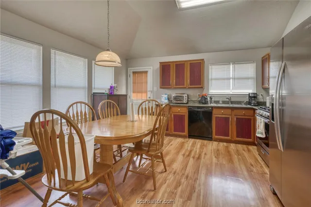 a kitchen with granite countertop stainless steel appliances a sink a stove a refrigerator cabinets and dining table