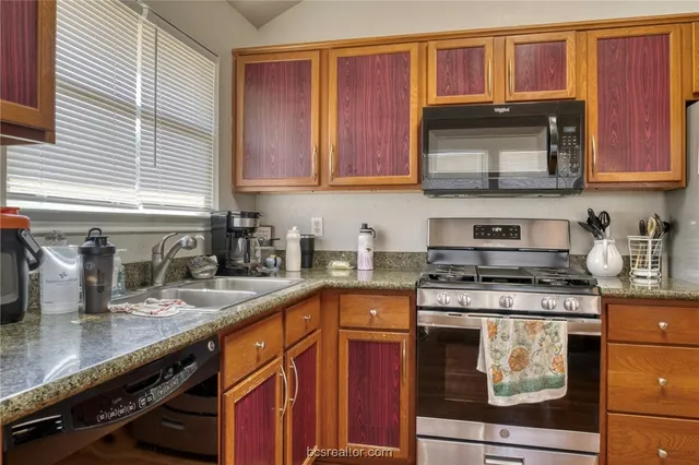 a kitchen with stainless steel appliances granite countertop a sink stove and cabinets