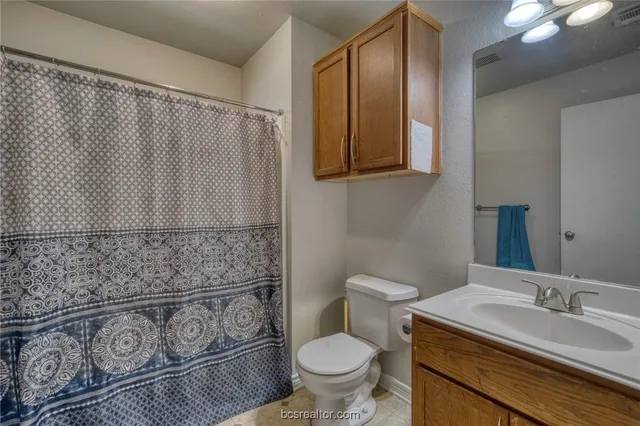 a bathroom with a granite countertop sink and a toilet
