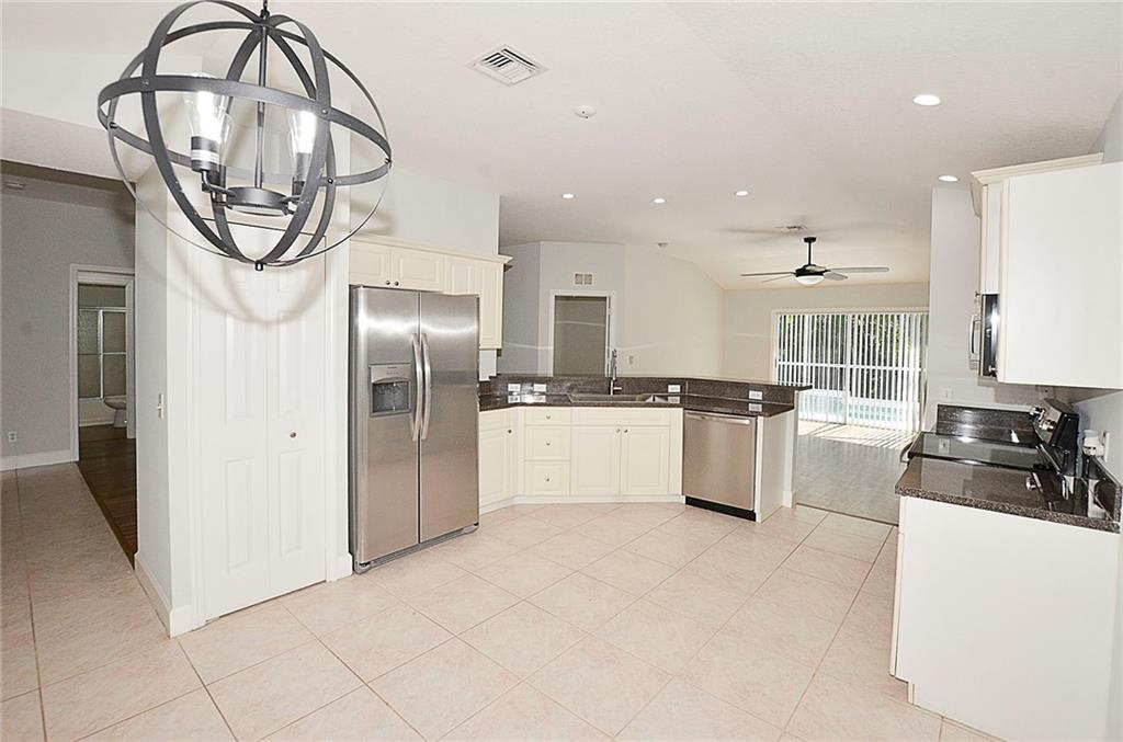 3285 3rd Place Vero Beach, FL 32968 - Photo 12 of 34 a kitchen with stainless steel appliances granite countertop a refrigerator a stove and a sink