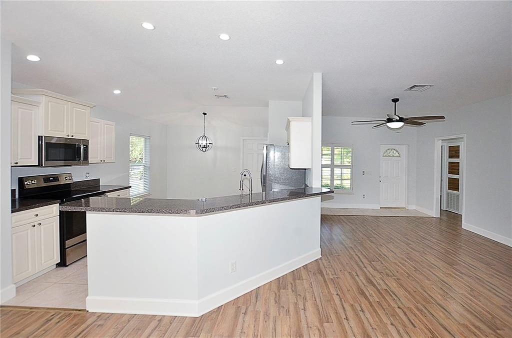 3285 3rd Place Vero Beach, FL 32968 - Photo 16 of 34 a large kitchen with stainless steel appliances kitchen island a large counter top and wooden floors