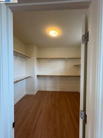 a living room with walk in closet and wooden floor