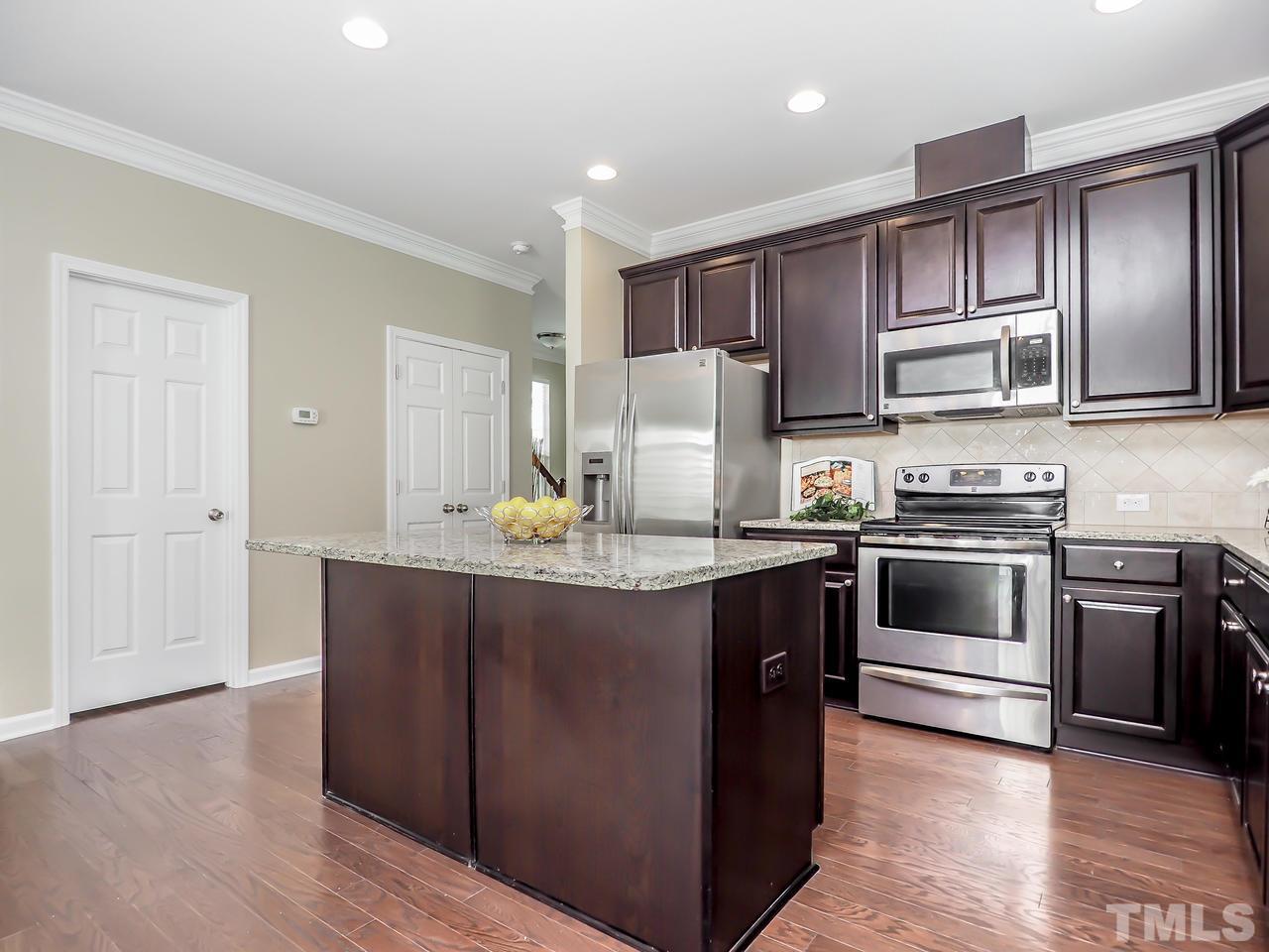 934 Ileagnes Road Raleigh, NC 27603 - Photo 7 of 23 a kitchen with kitchen island granite countertop wooden cabinets and stainless steel appliances