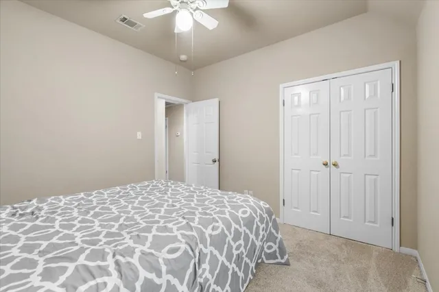 a bedroom with a large bed and a chandelier fan