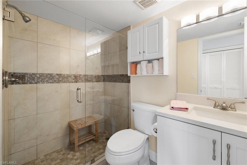 5 High Point Circle West, Unit 307 Naples, FL 34103 - Photo 18 of 31 Full bath featuring vanity, a shower stall, and a closet