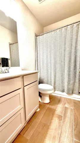 a bathroom with a sink a toilet a window and shower curtain