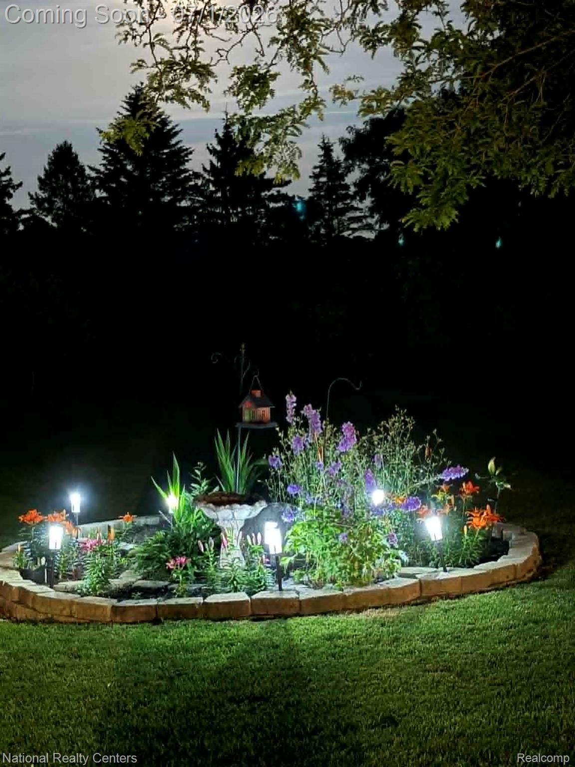 1330 Brauer Road Oxford, MI 48371 - Photo 12 of 54 Curved stone garden bed featuring various plantings, integrated lighting, and a central bird bath