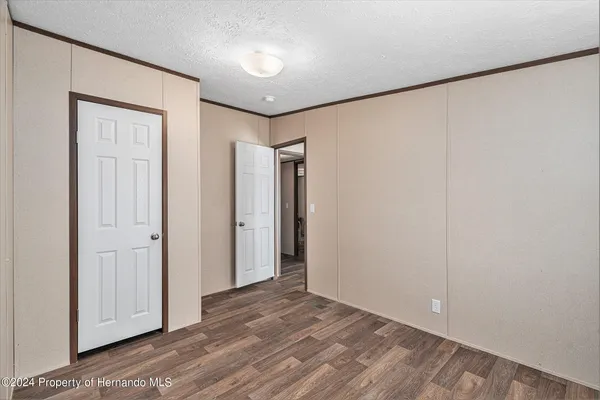 a view of an empty room with a window and dresser