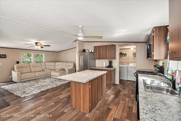 a kitchen with stainless steel appliances granite countertop a refrigerator a sink dishwasher a stove with wooden floors and cabinets