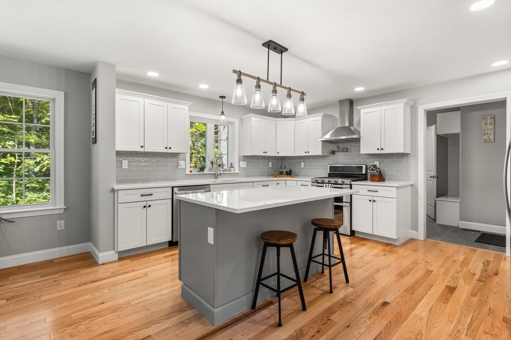 62 Benjamin Road Shirley, MA 01464 - Photo 5 of 37 a kitchen with kitchen island granite countertop wooden floors white cabinets and stainless steel appliances