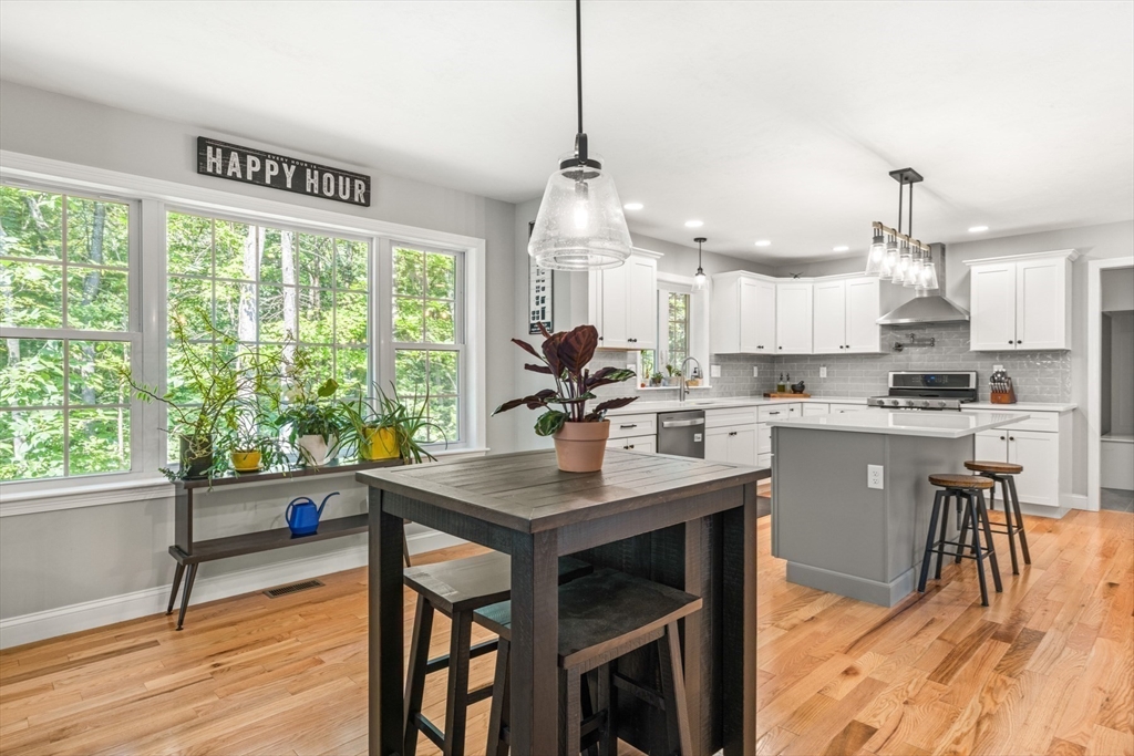 62 Benjamin Road Shirley, MA 01464 - Photo 9 of 37 a kitchen with stainless steel appliances granite countertop a stove a refrigerator a sink dishwasher a dining table and chairs with wooden floor