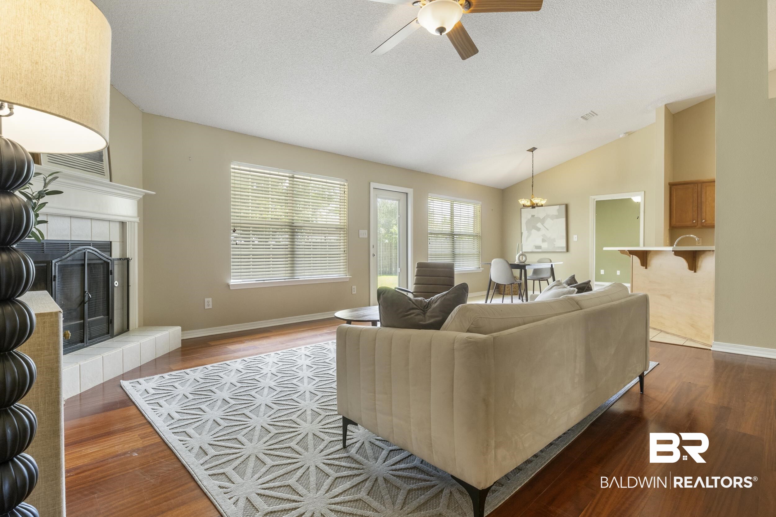 9610 Watkins Drive Fairhope, AL 36532 - Photo 24 of 26 Living room with vaulted ceiling, a tiled fireplace, ceiling fan with notable chandelier, and hardwood / wood-style floors