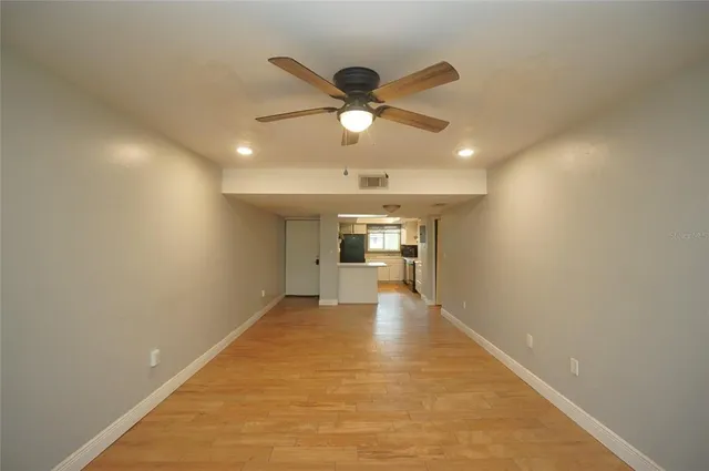 a view of a livingroom with a ceiling fan and kitchen view