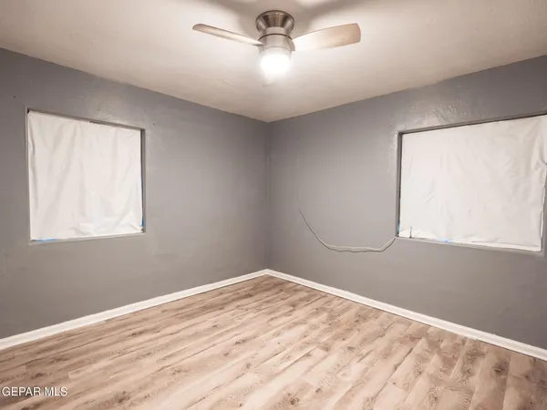 a view of empty room with wooden floor and fan