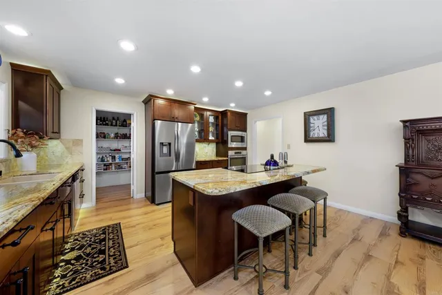 a dining hall with stainless steel appliances granite countertop a stove and a dining table