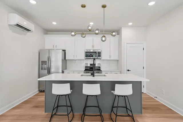 a kitchen with stainless steel appliances kitchen island granite countertop a dining table chairs and white cabinets