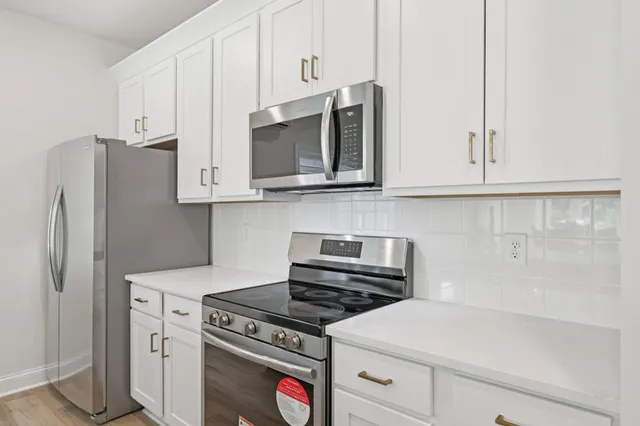 a kitchen with stainless steel appliances white cabinets and a stove a refrigerator with white cabinets