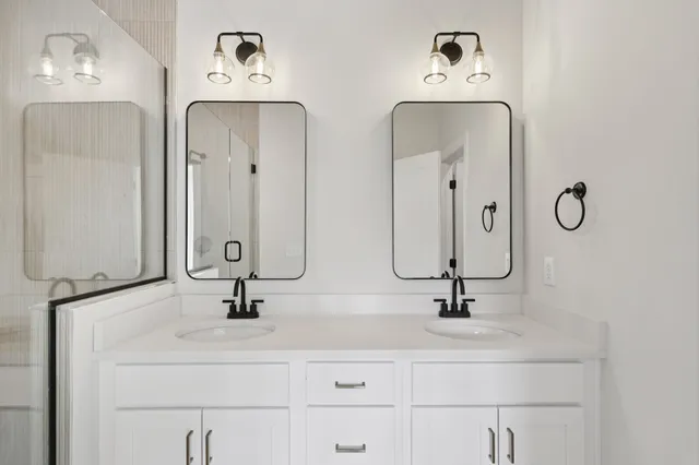 a bathroom with double vanity sinks and two mirror