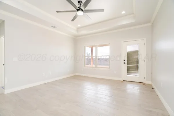 an empty room with wooden floor fan and windows