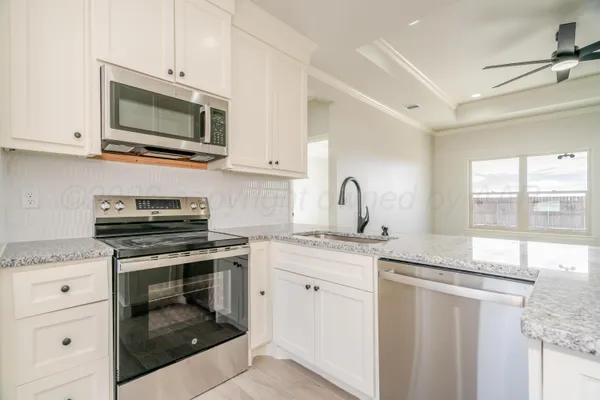 a kitchen with granite countertop a sink stainless steel appliances and white cabinets