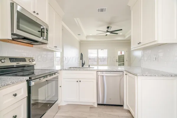 a kitchen with stainless steel appliances granite countertop a stove a sink and a microwave