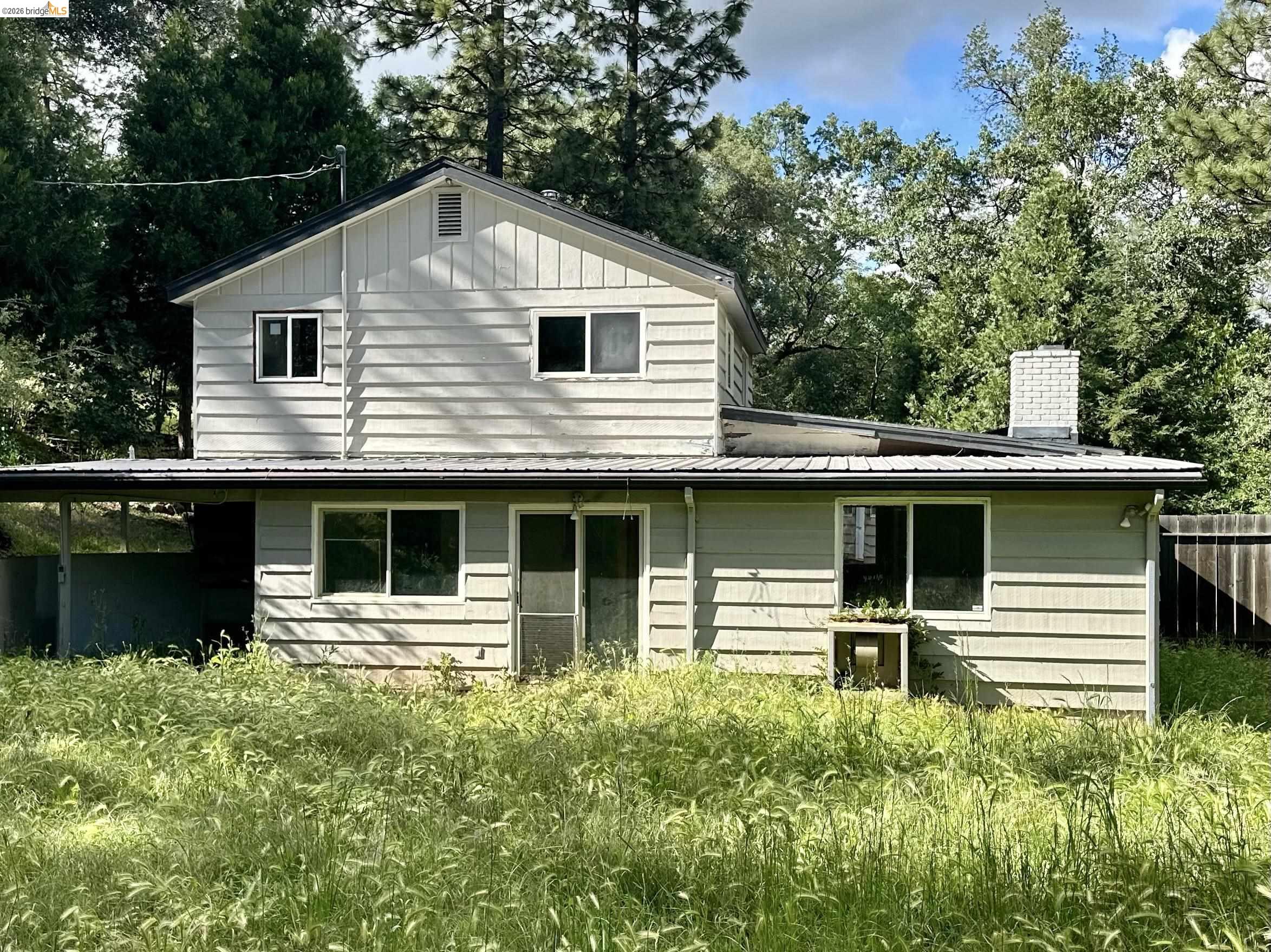 20231 Hidden Acres Road Sonora, CA 95370 - Photo 2 of 25 Two-story residence featuring light-colored horizontal siding and a prominent brick chimney