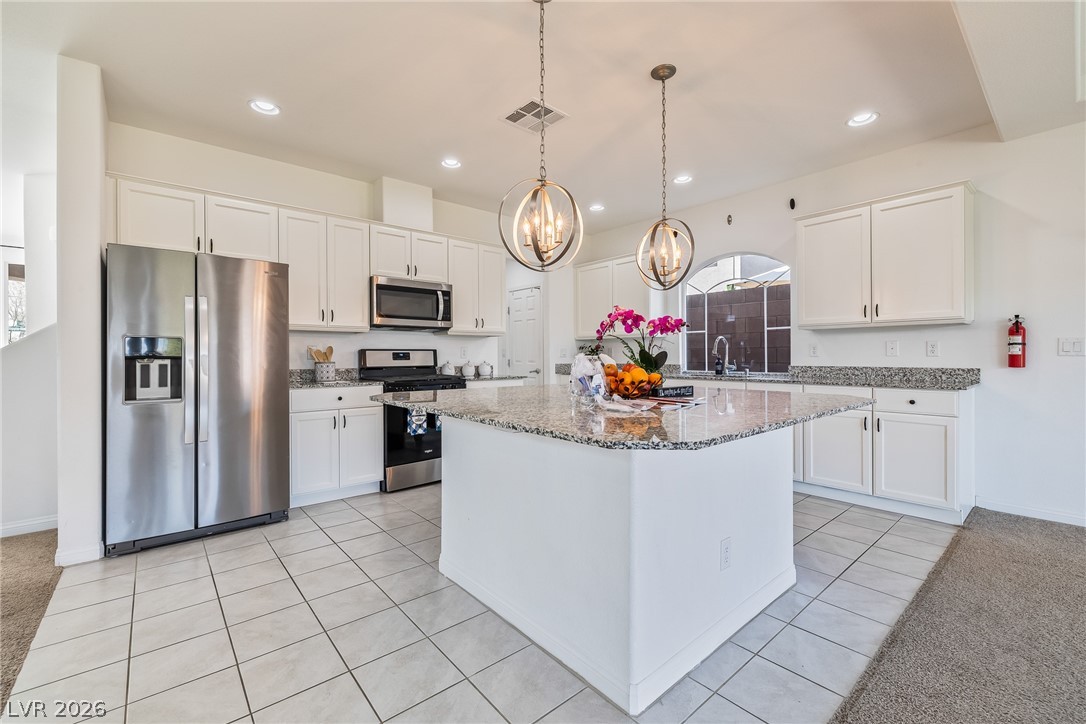 5510 Ripple Ridge Avenue Las Vegas, NV 89139 - Photo 20 of 45 This kitchen showcases a functional island with elegant pendant lighting and practical stainless steel appliances.