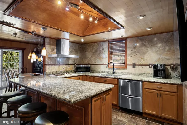a kitchen with granite countertop kitchen island stainless steel appliances a sink stove and cabinets