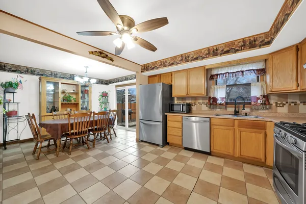 a kitchen with a dining table chairs stainless steel appliances and cabinets