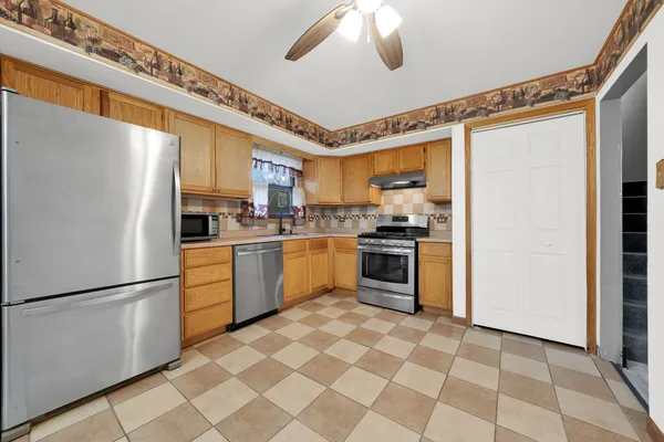 a kitchen with stainless steel appliances granite countertop a refrigerator a sink dishwasher a stove with white cabinets and wooden floor