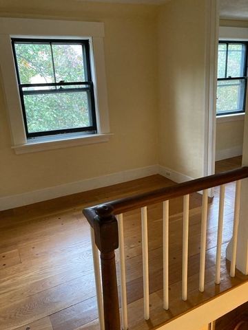 a view of a hallway with wooden floor and a window
