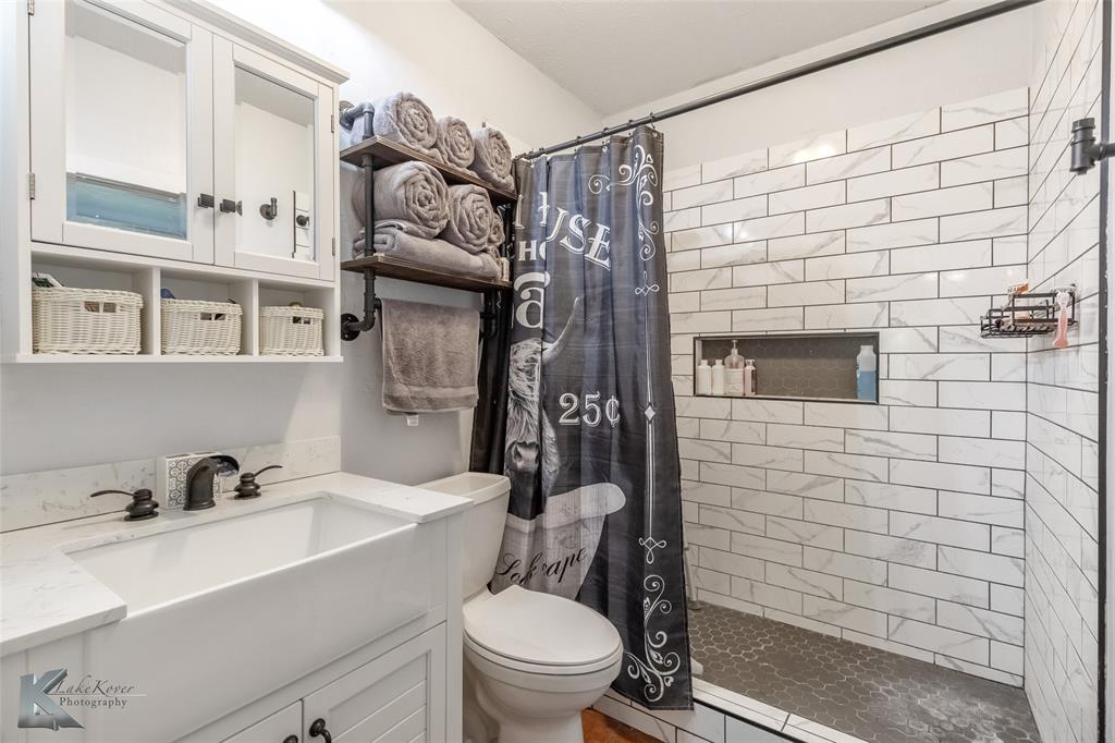 202 East Ross Street Rising Star, TX 76471 - Photo 24 of 40 a bathroom with a sink a toilet and shower curtain