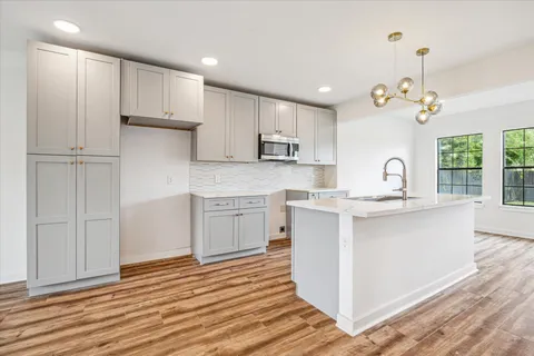 a kitchen with stainless steel appliances granite countertop a sink a stove a refrigerator and wooden floor