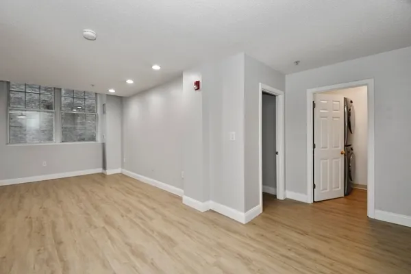 a view of an empty room with wooden floor and a window