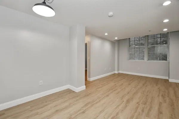an empty room with wooden floor and windows